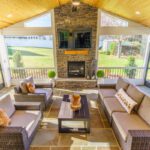 A screened porch with vaulted wood ceiling, stone fireplace, and flagstone floor, custom built by Carolina Decks in the Kings Mountain, NC area.