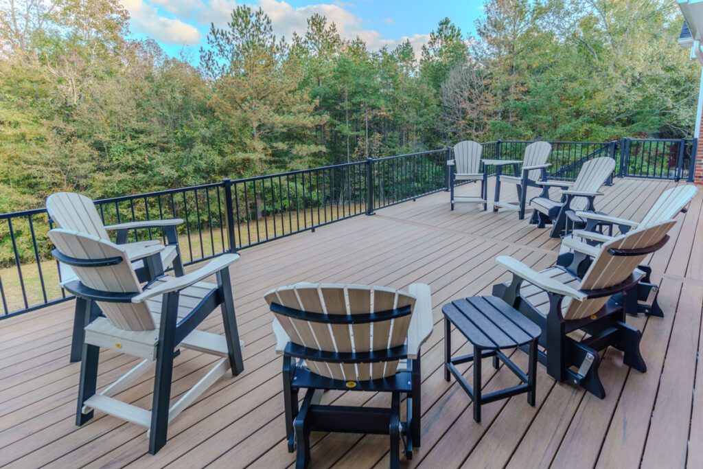 Spacious elevated light brown composite deck with black metal railing and Adirondack chairs, custom built by Carolina Decks in the Lake Wylie, NC area.