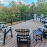 Spacious elevated light brown composite deck with black metal railing and Adirondack chairs, custom built by Carolina Decks in the Lake Wylie, NC area.