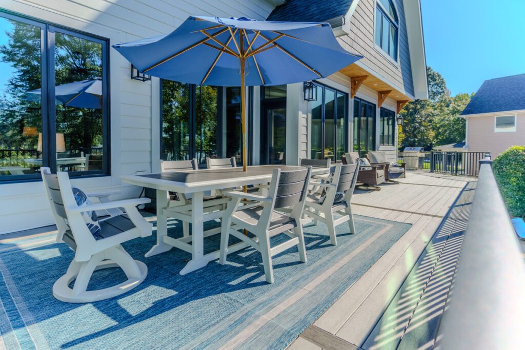 Spacious composite deck with elegant black aluminum railing, blue umbrella, and outdoor dining area, custom built by Carolina Decks in the Lake Norman area.