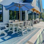 Spacious composite deck with elegant black aluminum railing, blue umbrella, and outdoor dining area, custom built by Carolina Decks in the Lake Norman area.