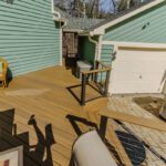 Modern light brown composite deck featuring sleek cable railing and adjacent paver patio, custom built by Carolina Decks in the Belmont, NC area.