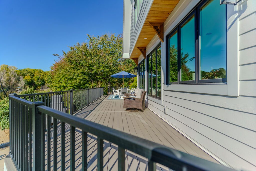 Modern gray composite deck with sleek black metal railings and architectural wooden soffit details, custom built by Carolina Decks in the Lake Norman, NC area.