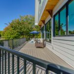 Modern gray composite deck with sleek black metal railings and architectural wooden soffit details, custom built by Carolina Decks in the Lake Norman, NC area.