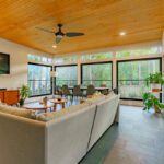 Modern sunroom with wide black windows, wood ceiling, and dark tile floor, custom built by Carolina Decks in the Rhone, NC area.