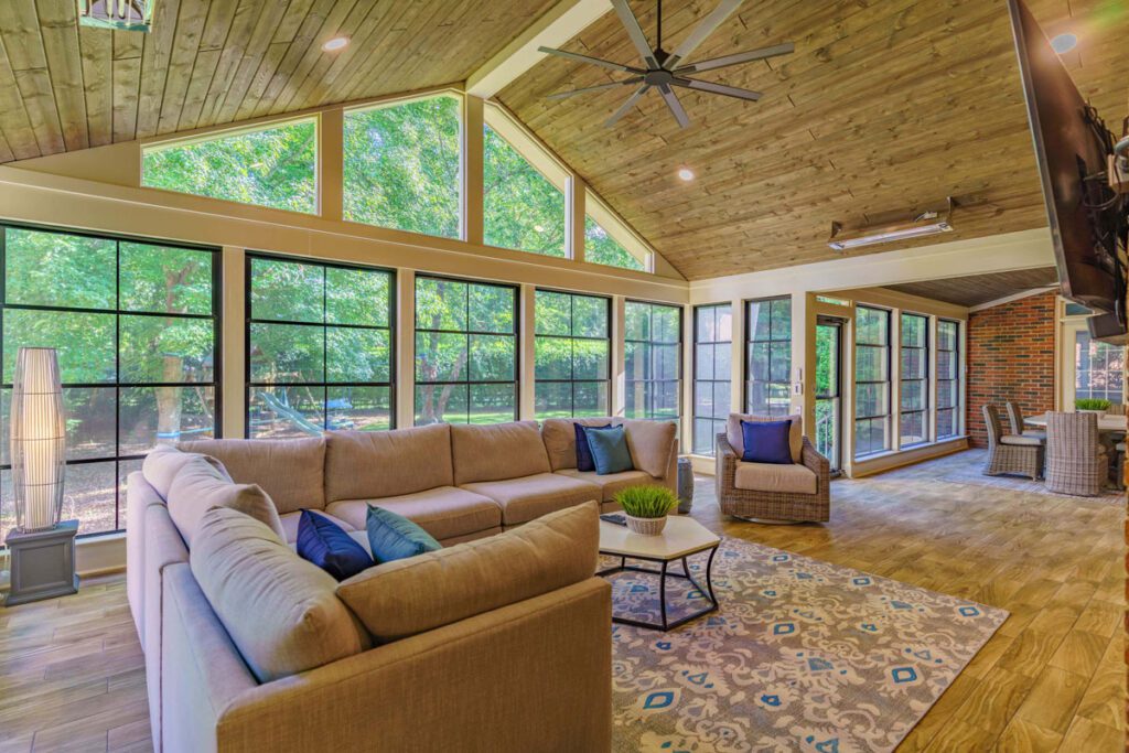 Spacious sunroom with vaulted wood ceiling, black-grid windows, and wood-look tile, custom built by Carolina Decks in Wessex Square.