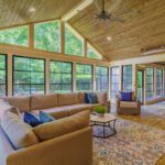 Spacious sunroom with vaulted wood ceiling, black-grid windows, and wood-look tile, custom built by Carolina Decks in Wessex Square.