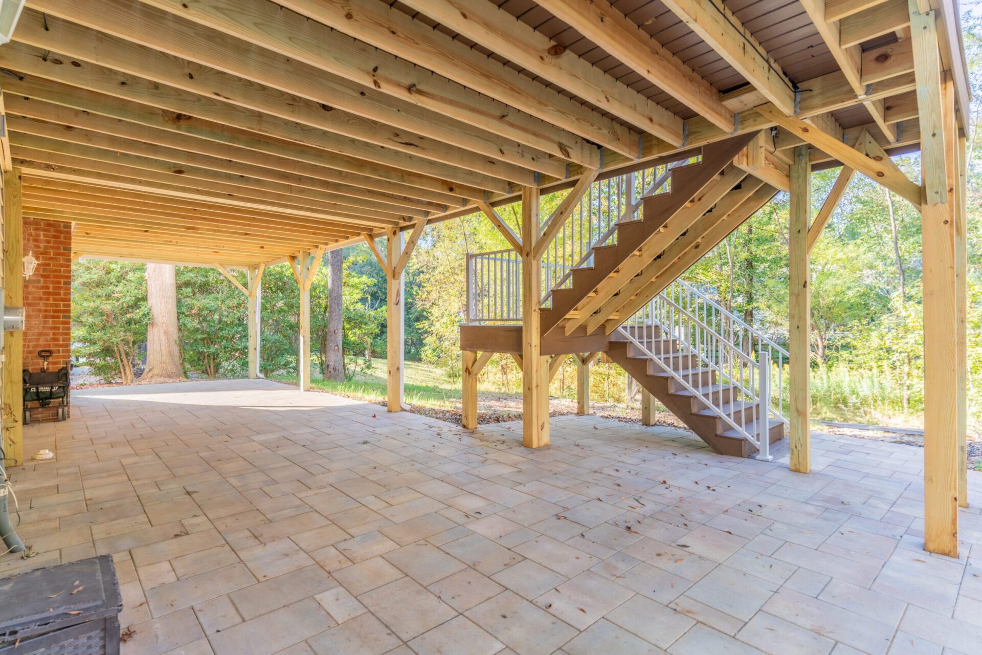 Custom pressure-treated wood deck with integrated stairs and a stone paver patio underneath in the Carmel neighborhood.