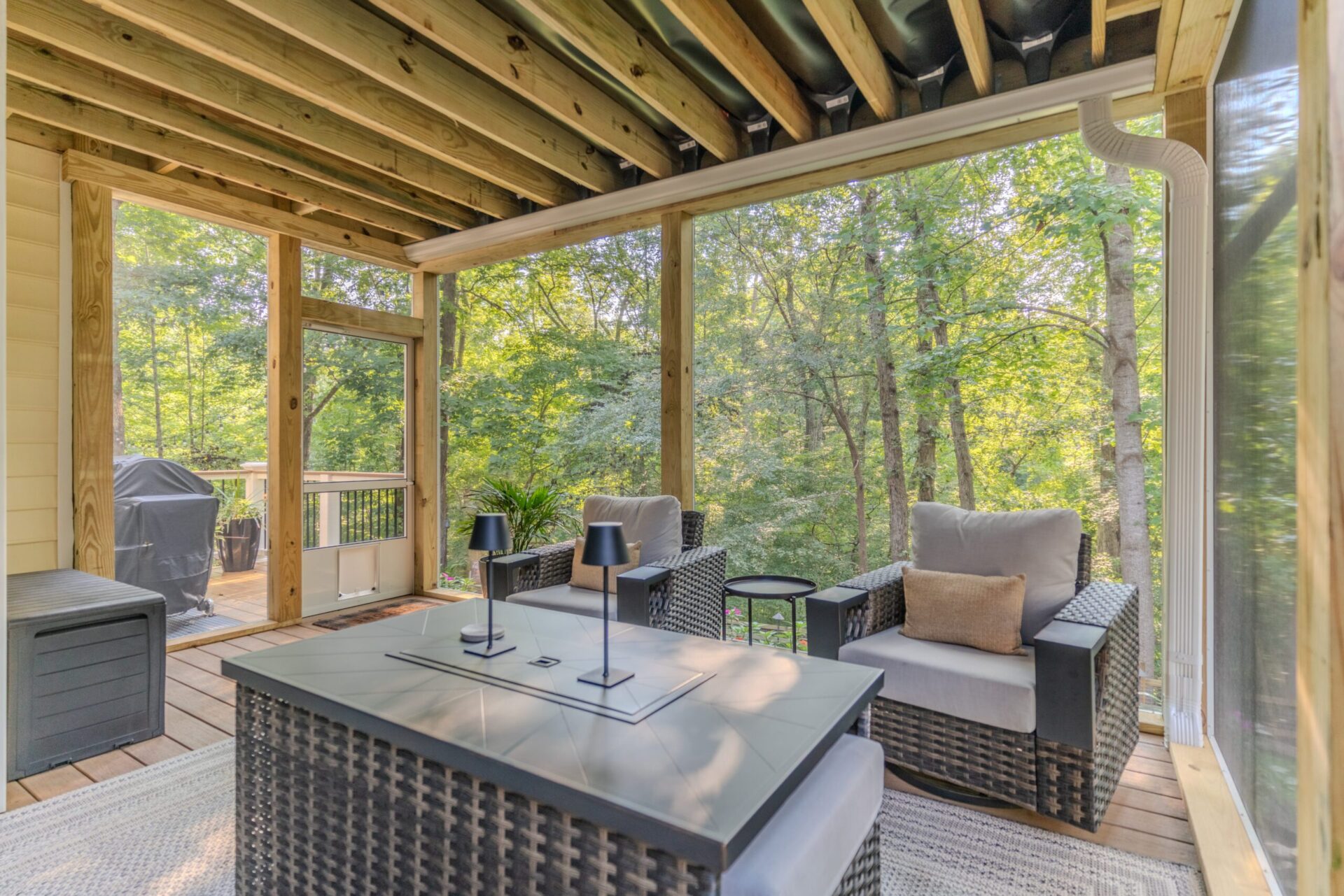Interior of a lower-level screened porch in Charlotte's Sardis Forest neighborhood, showcasing an under-deck drainage ceiling system over a comfortable seating area with TimberTech Antique Leather flooring.