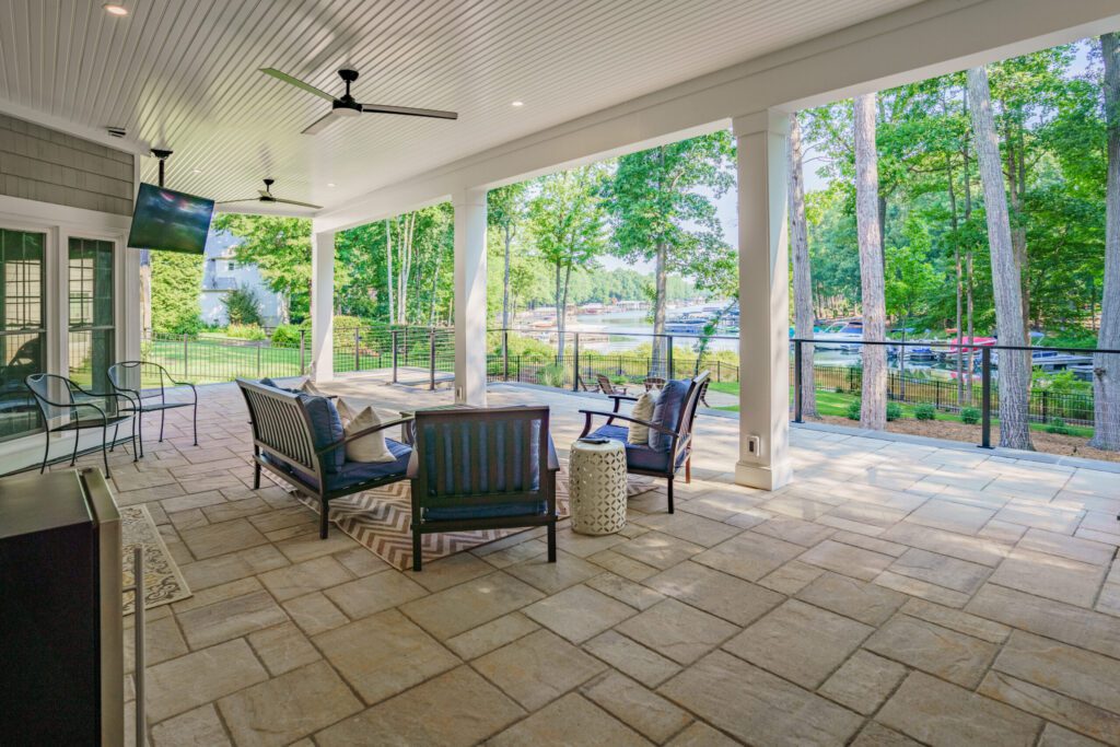 Lower-level covered patio with stone pavers and ceiling fans facing a Lake Norman dock.