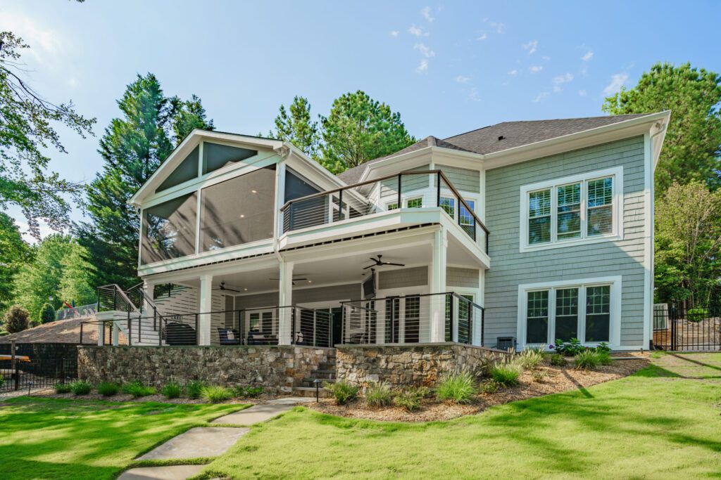 Rear exterior of a home showing a stone retaining wall and multi-level deck construction.