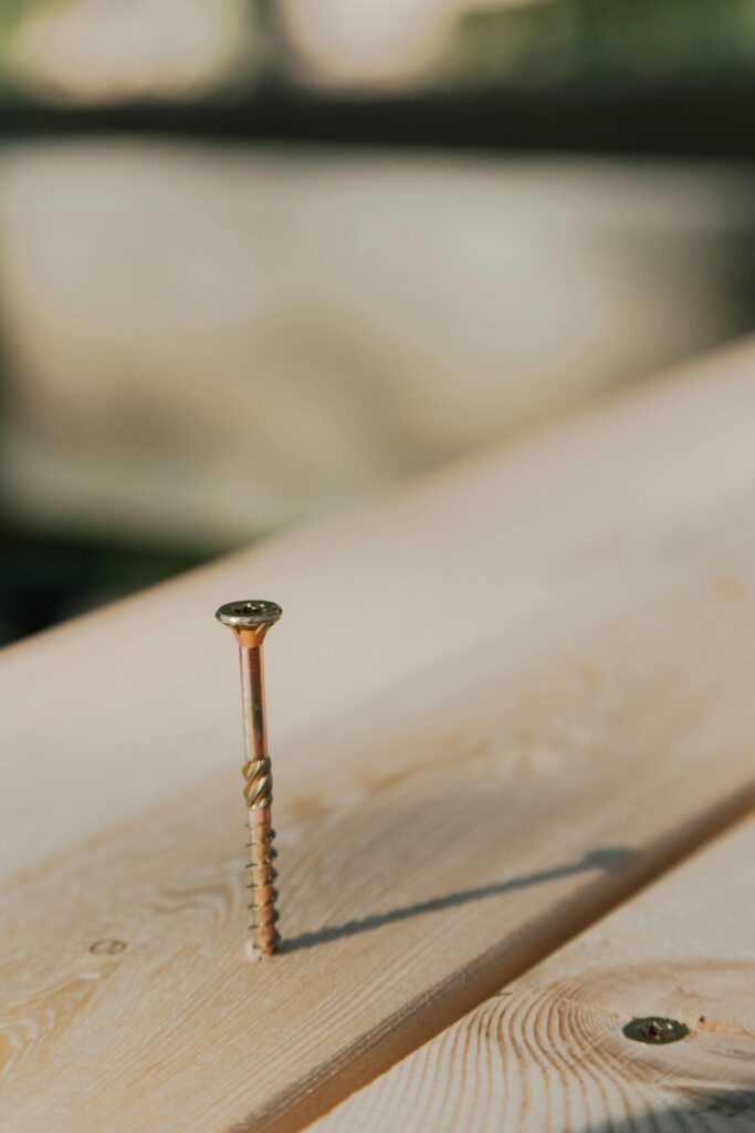 Close-up of traditional face screws in a pressure-treated wood deck showing visible hardware.