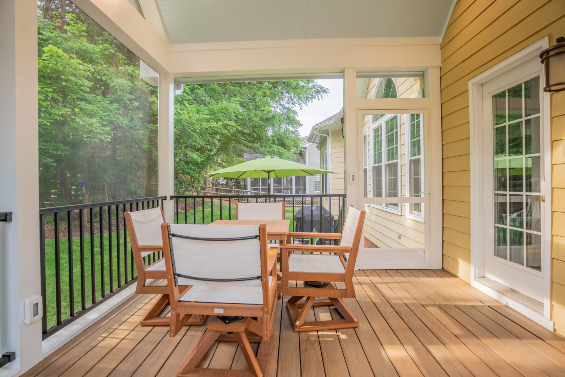 Custom Screeneze screened porch in the Thornhill and Ballantyne neighborhood of South Charlotte, featuring TimberTech Tigerwood composite decking, Trex black aluminum railing, and an outdoor dining set looking out toward a paver patio.