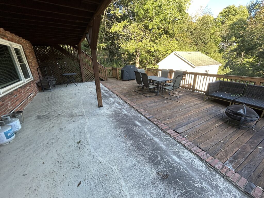 An aging wood deck and stained concrete patio on a brick home in Charlotte's Stonehaven neighborhood prior to a custom composite deck remodel.