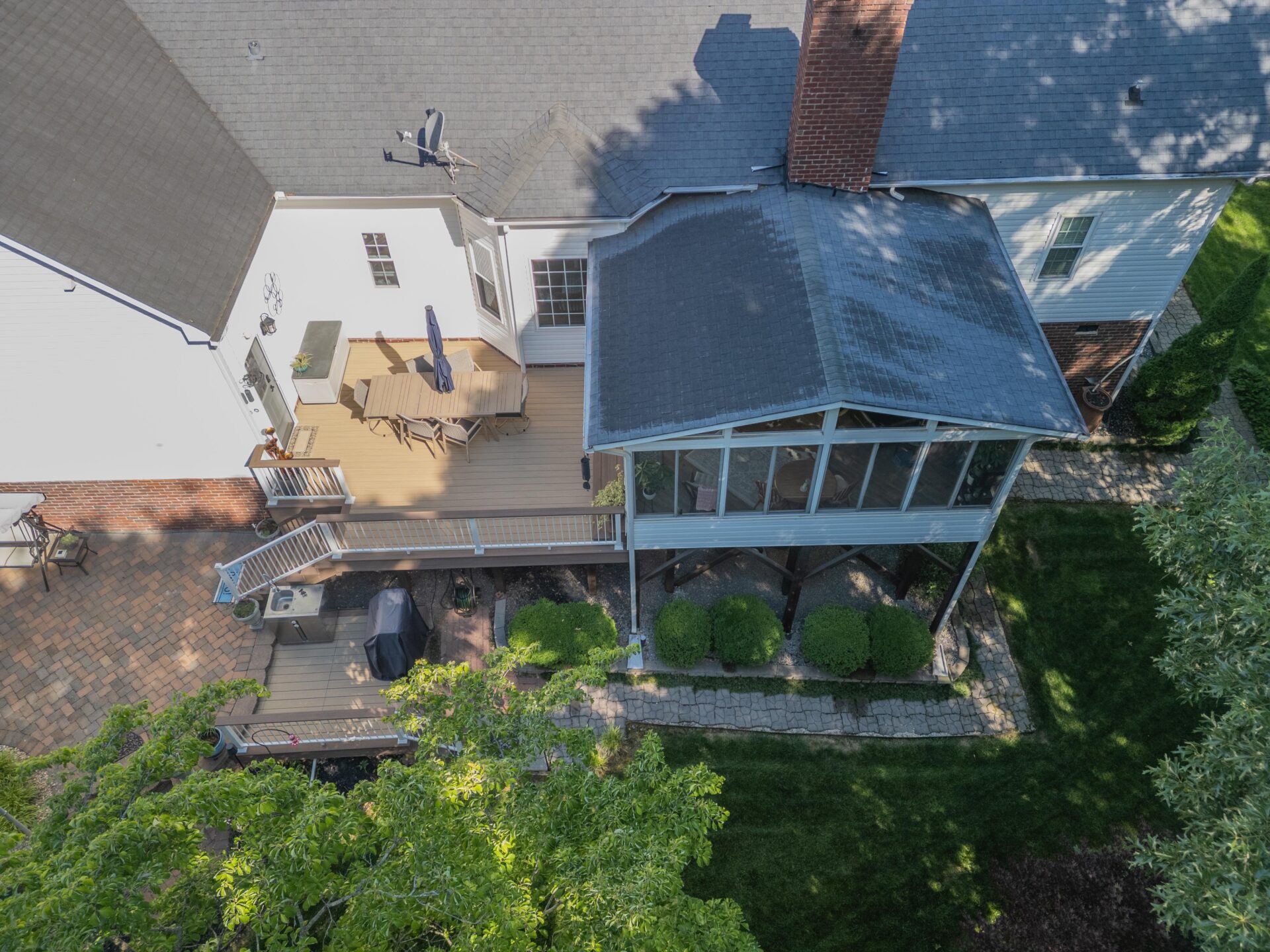 Aerial drone view of a multi-level custom deck resurface using TimberTech composite materials alongside an integrated screen porch addition.