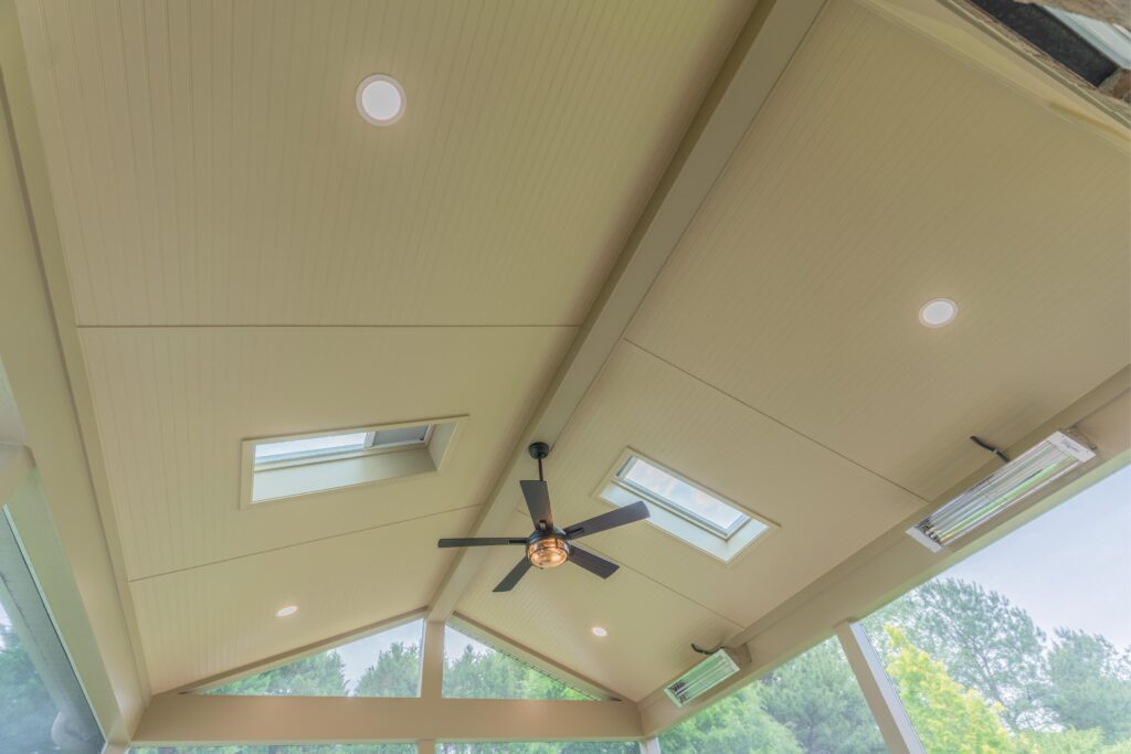 A high vaulted porch ceiling featuring double integrated skylights, a modern black ceiling fan, recessed lighting, and dual Infratech heaters.