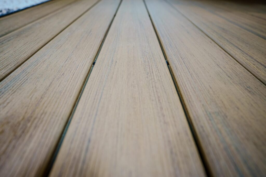 Close-up macro view of premium brown composite decking boards installed with a hidden fastener system, showing clean sightlines and zero exposed screws.