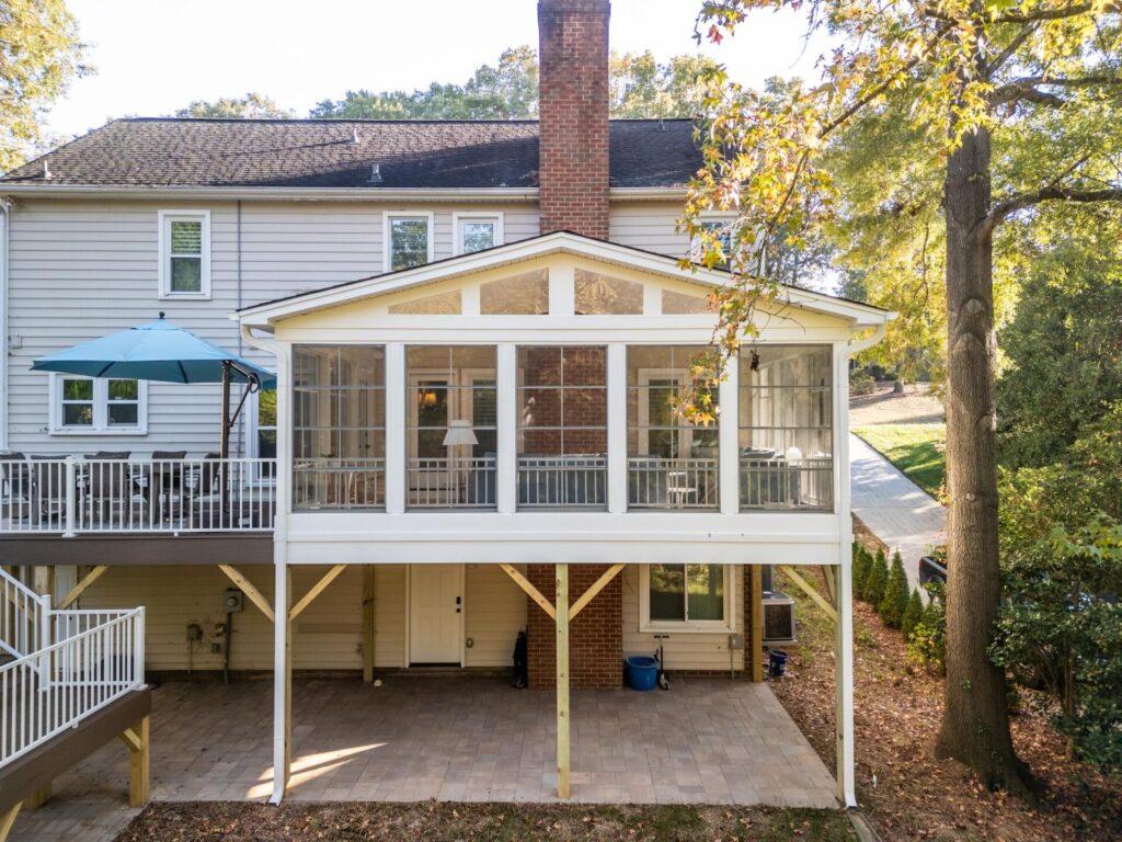 Elevated Eze-Breeze 3-season porch addition with vinyl windows and a lower-level paver patio in Carmel Charlotte.