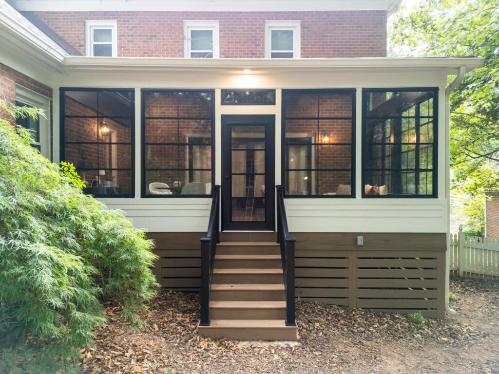 Exterior view of a black-framed Eze-Breeze screened porch enclosure with composite steps and Infratech heating in Colvard Park Charlotte.