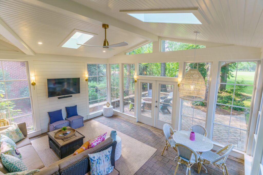 Bright Eze-Breeze 3-season porch in Providence Country Club Charlotte featuring a white shiplap accent wall, skylights, and cozy seating.
