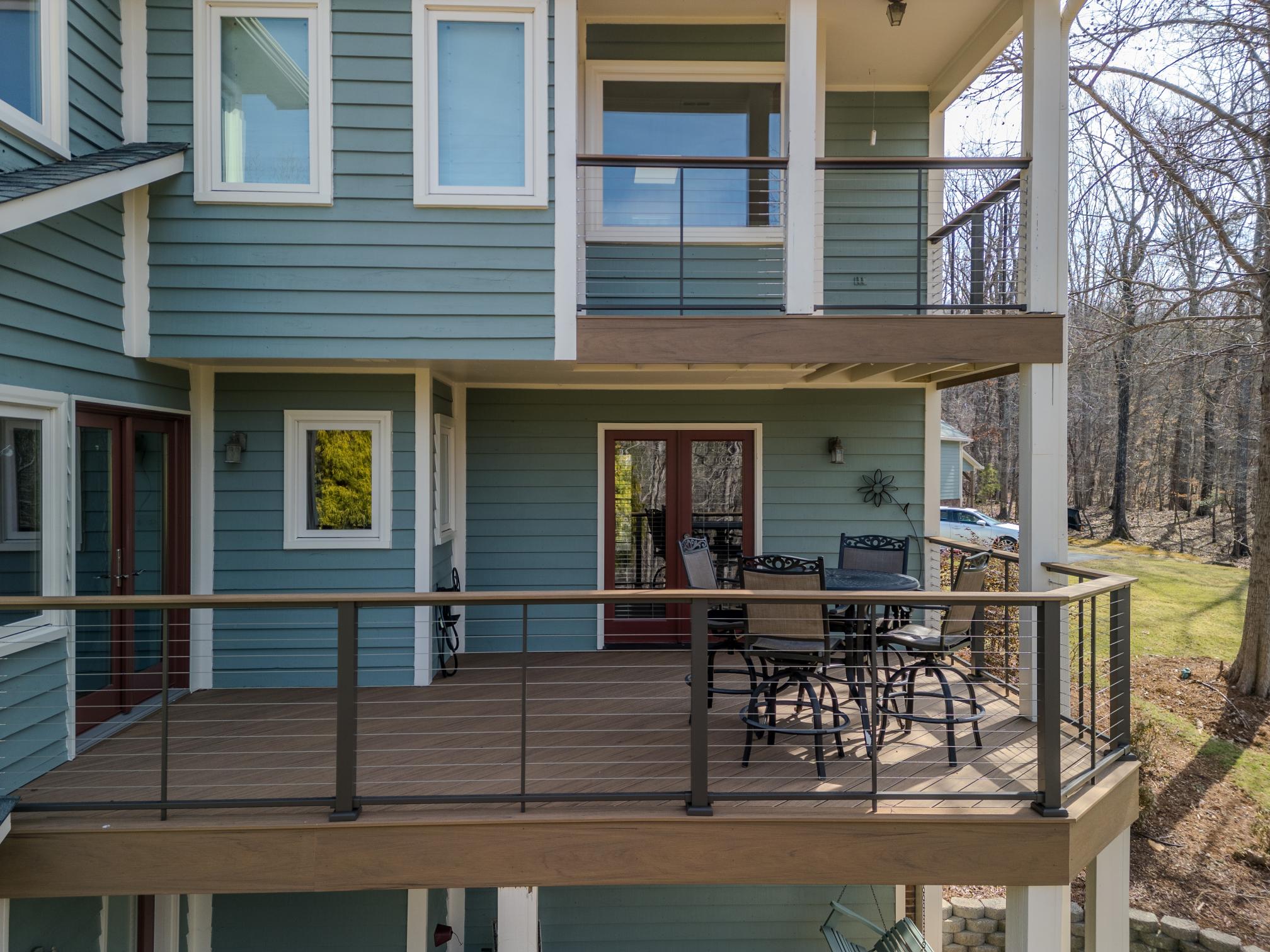 Exterior view of a two-story blue home featuring a resurfaced deck built with TimberTech Antique Leather decking and horizontal cable railings.