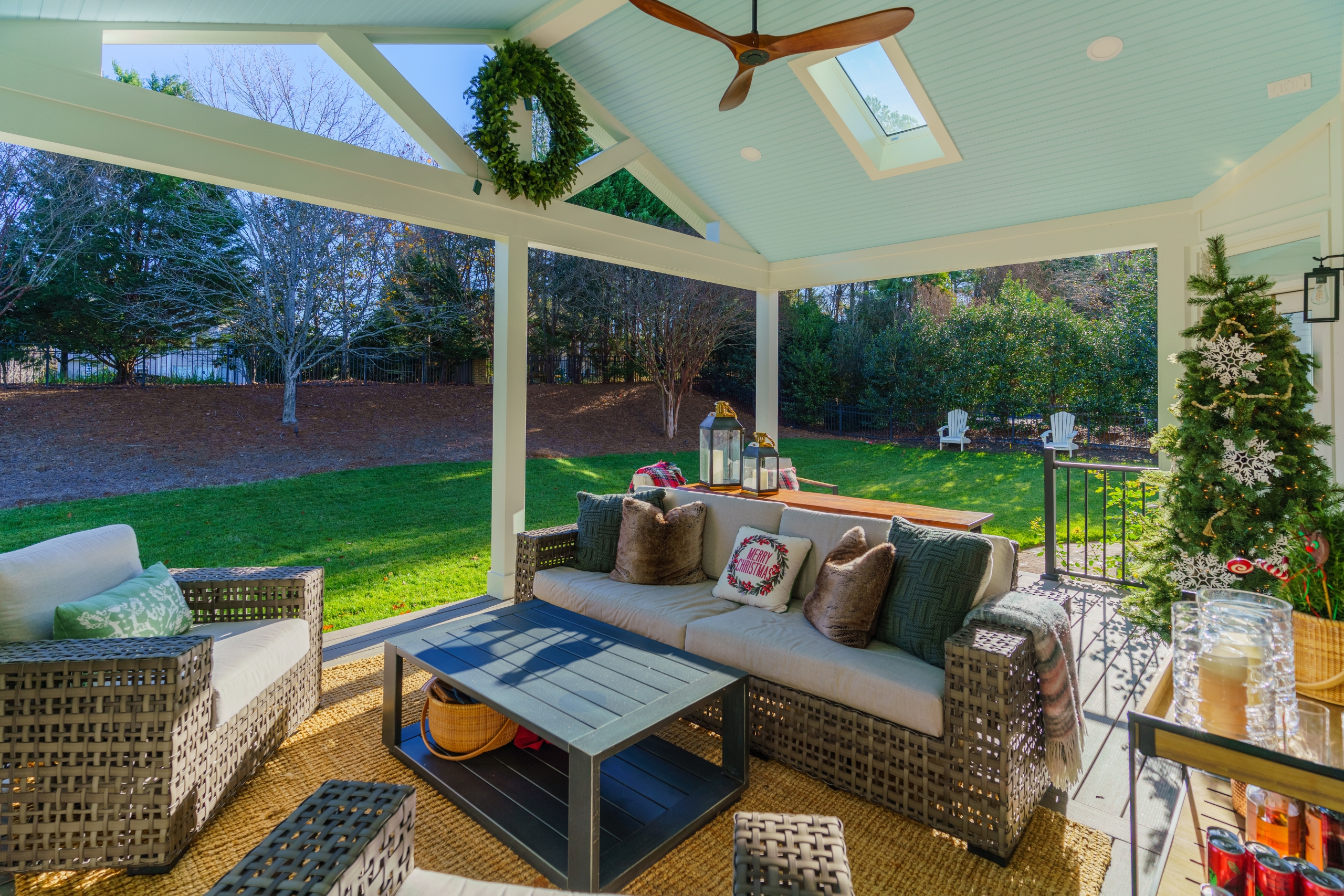 Modern white patio cover design with an integrated skylight, light blue beadboard ceiling, and a wooden ceiling fan.