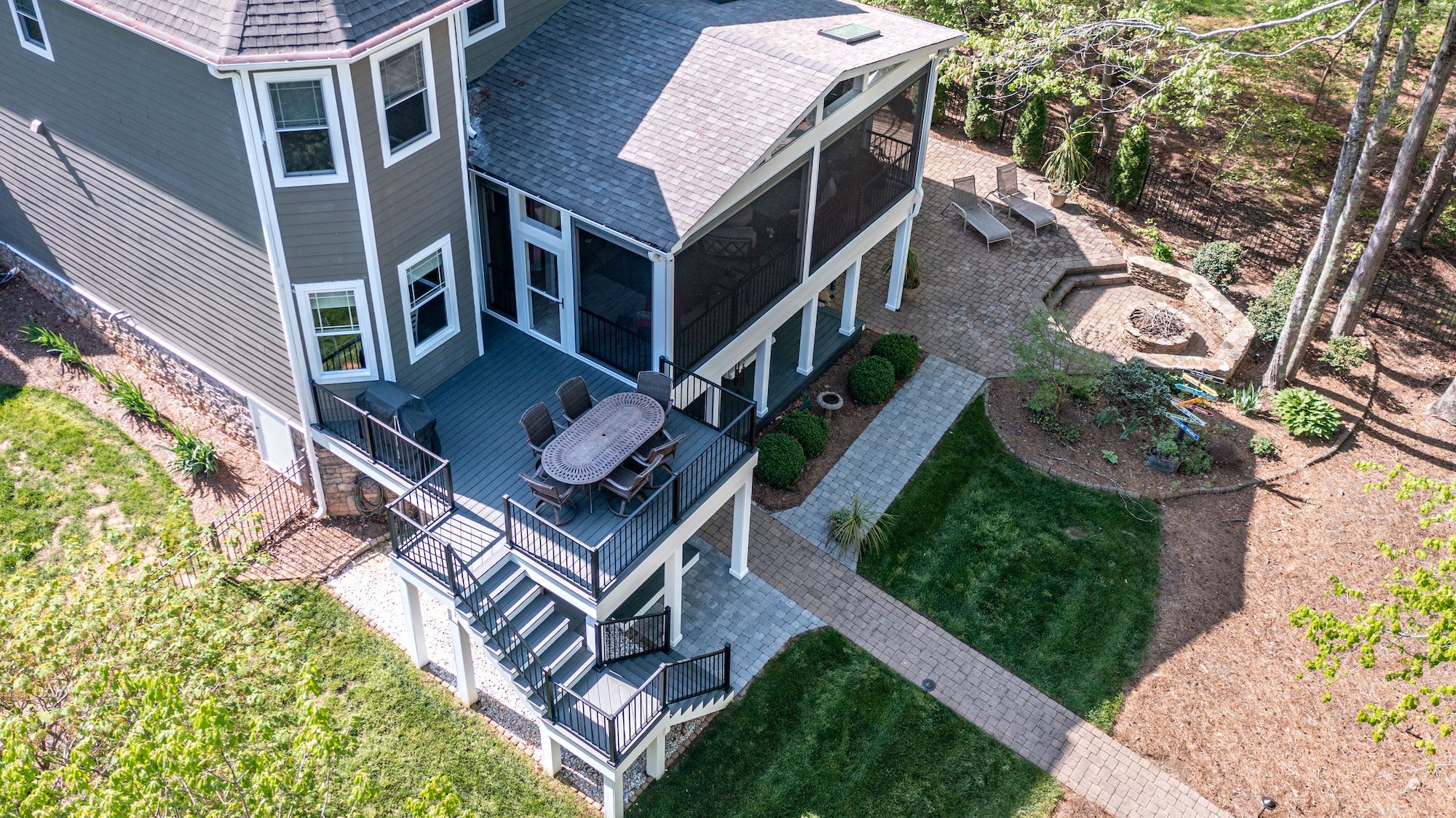 Full backyard view of a premium home addition with a white screened porch, attached open deck, and a grand vaulted roof design on the Webbs Chapel project.