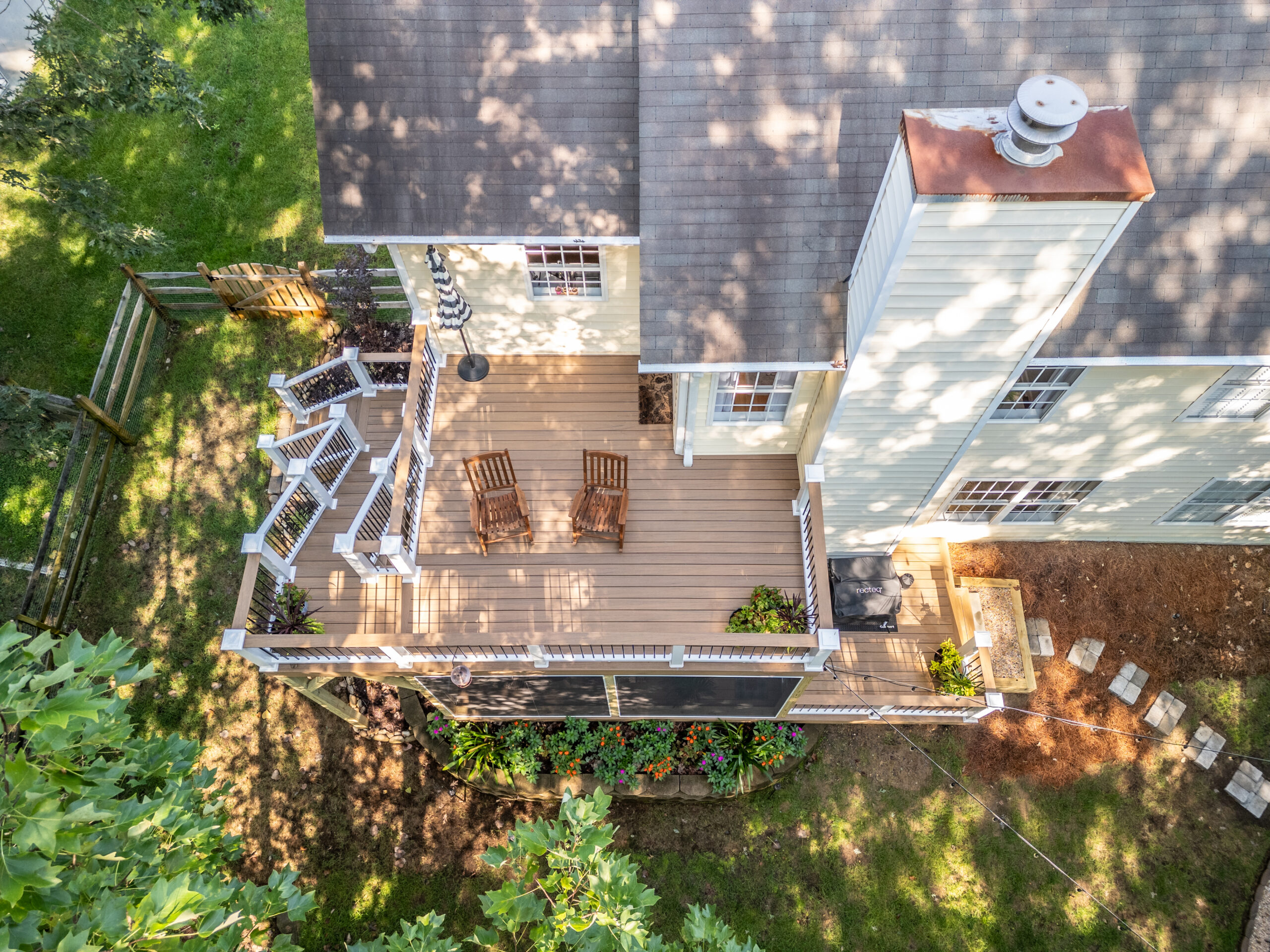 Aerial drone view of a custom multi-level composite deck built with TimberTech Antique Leather decking and matching railings with black balusters in Charlotte's Sardis Forest neighborhood.