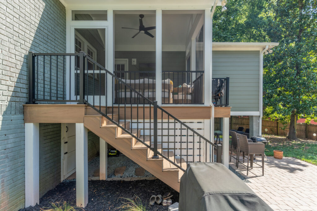 A backyard deck in Charlotte featuring black Trex aluminum railings on a staircase leading to a white screened-in porch.