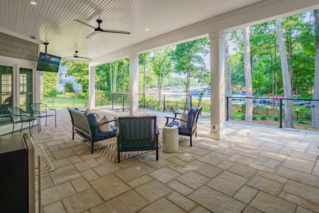 Lower-level covered patio with stone pavers and ceiling fans facing a Lake Norman dock.